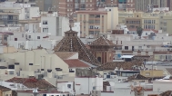 Vista de la cúpula y torre entre las casas del centro histórico de Málaga