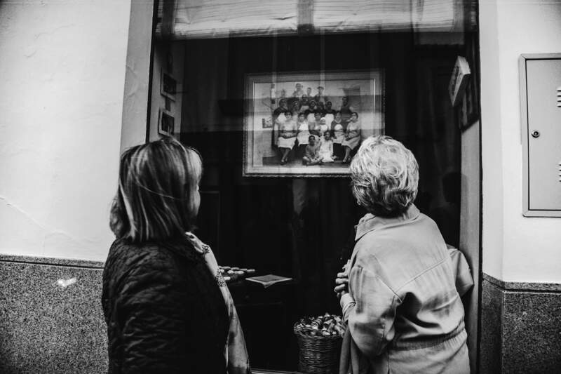 Dos mujeres observan una fotografía antigua en blanco y negro, exhibida detrás de un cristal. La imagen refleja un grupo de trabajadoras unidas para hacerse la foto.